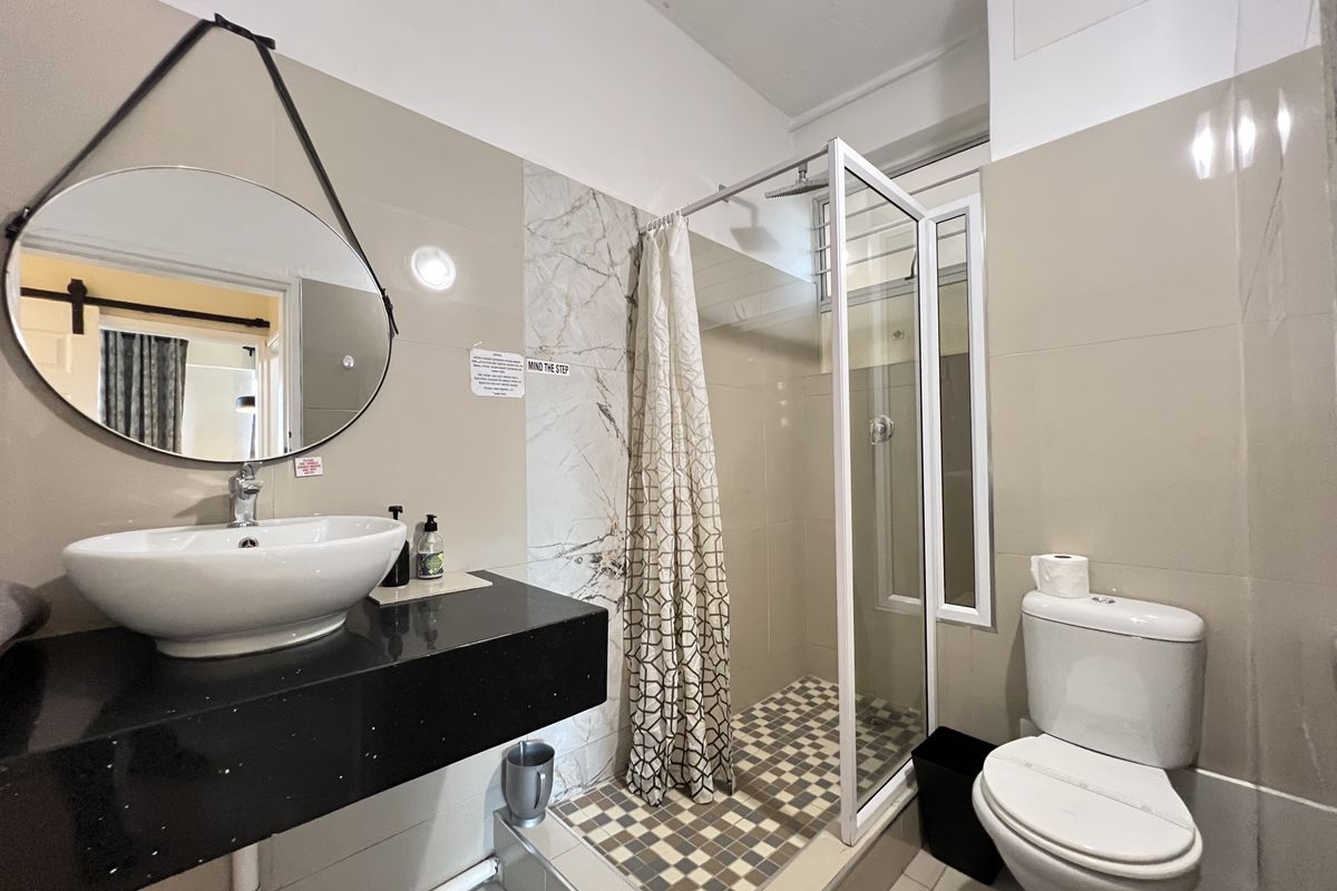A compact bathroom featuring a floating vanity with a vessel sink, a walk-in shower with a glass enclosure, and a standard toilet.