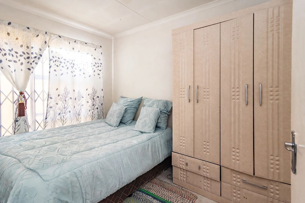 A functional bedroom featuring a built-in wardrobe and a window fitted with a security gate, providing a practical and secure living space.