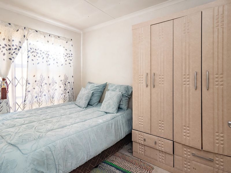 A functional bedroom featuring a built-in wardrobe and a window fitted with a security gate, providing a practical and secure living space.