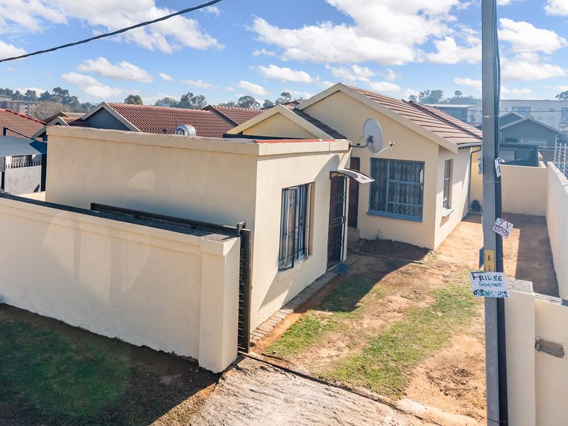Front exterior view of a single-story house featuring a tiled roof, perimeter wall, and security features.