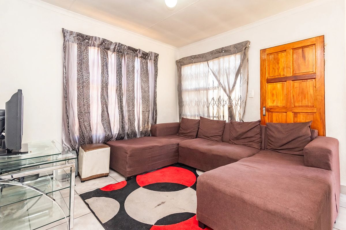 A functional living room featuring tiled flooring and a solid timber door, providing a neutral base for potential interior updates.