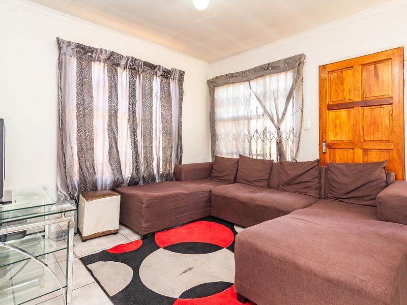 A functional living room featuring tiled flooring and a solid timber door, providing a neutral base for potential interior updates.