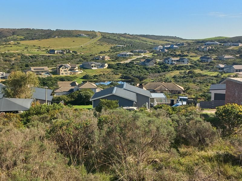 A wide-angle view overlooking a residential estate with natural vegetation and surrounding hills.