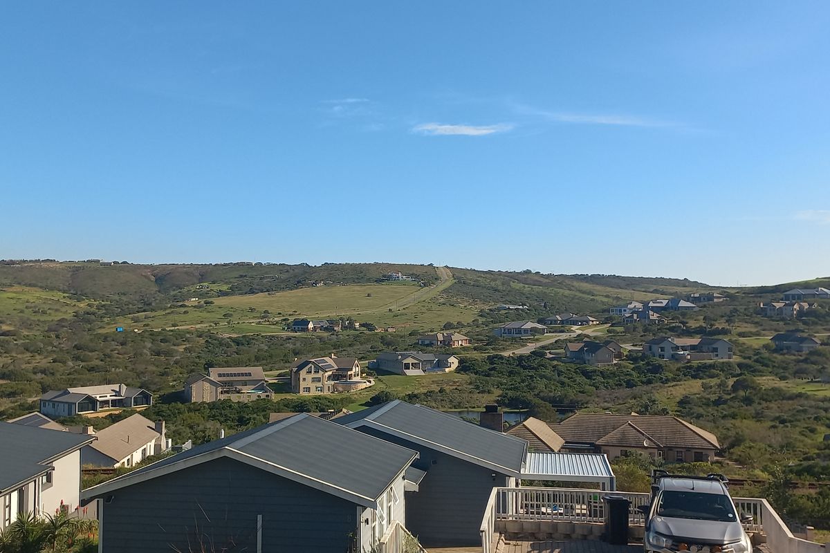 A scenic elevated view overlooking a residential estate with rolling hills and surrounding natural landscape.