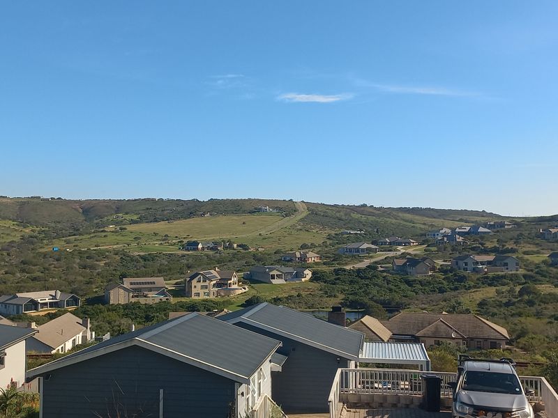 A scenic elevated view overlooking a residential estate with rolling hills and surrounding natural landscape.