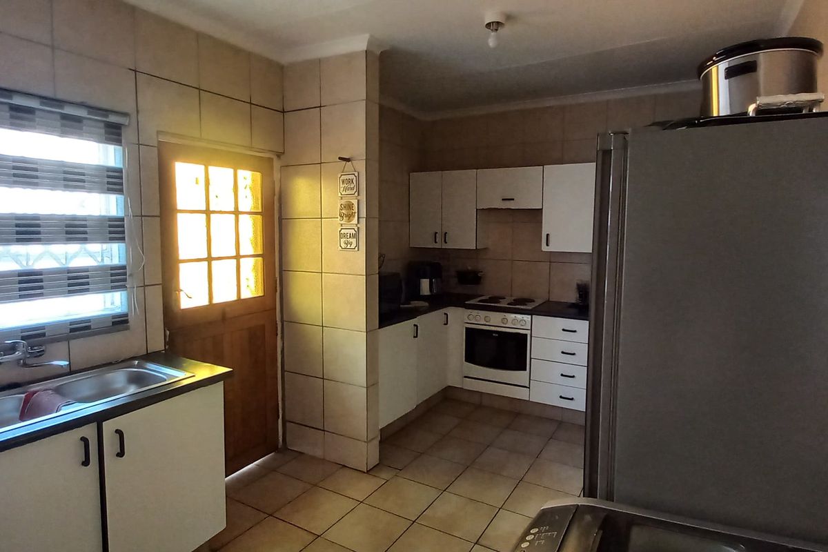 A functional kitchen featuring tiled walls, built-in cabinetry, a stove with an extractor fan, and a double-basin sink with a window view.