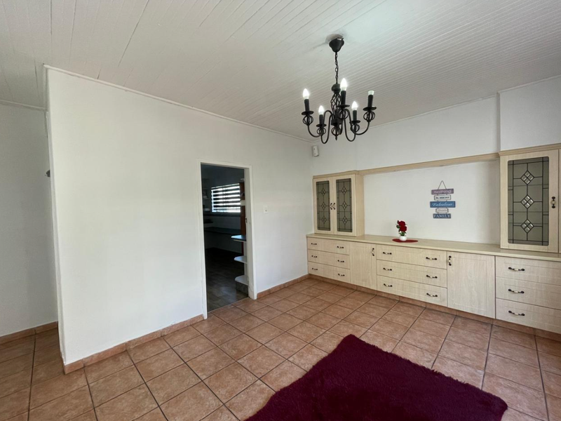A living area featuring built-in cabinetry, tiled flooring, and a classic chandelier, offering a functional space with potential for modern updates.