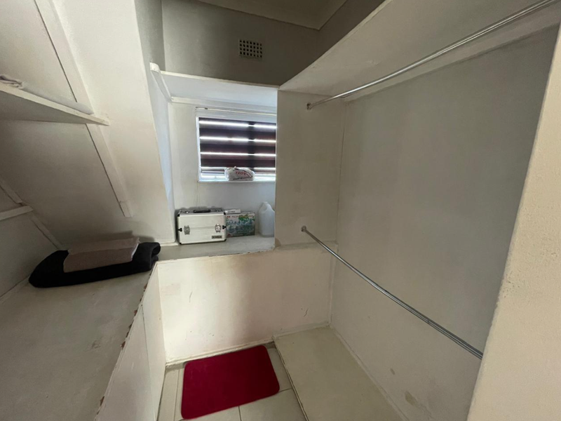 A small walk-in closet or storage area featuring built-in shelving and hanging rails, requiring minor cosmetic updates to improve its overall condition.