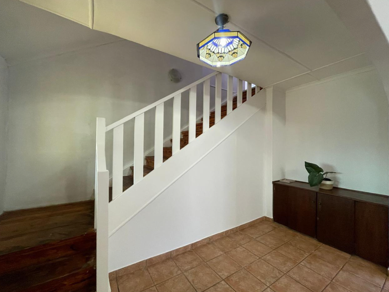 An entrance area featuring a staircase with wooden treads and a white balustrade, complemented by tiled flooring.