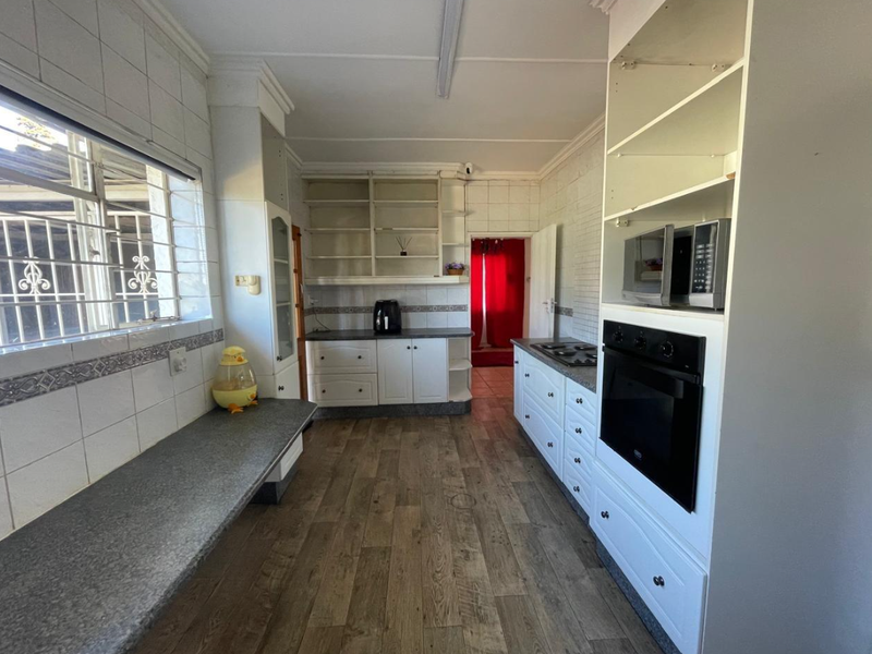 A functional kitchen featuring built-in cabinetry, a built-in oven, hob, and tiled splashbacks, offering a practical layout with potential for modern updates.
