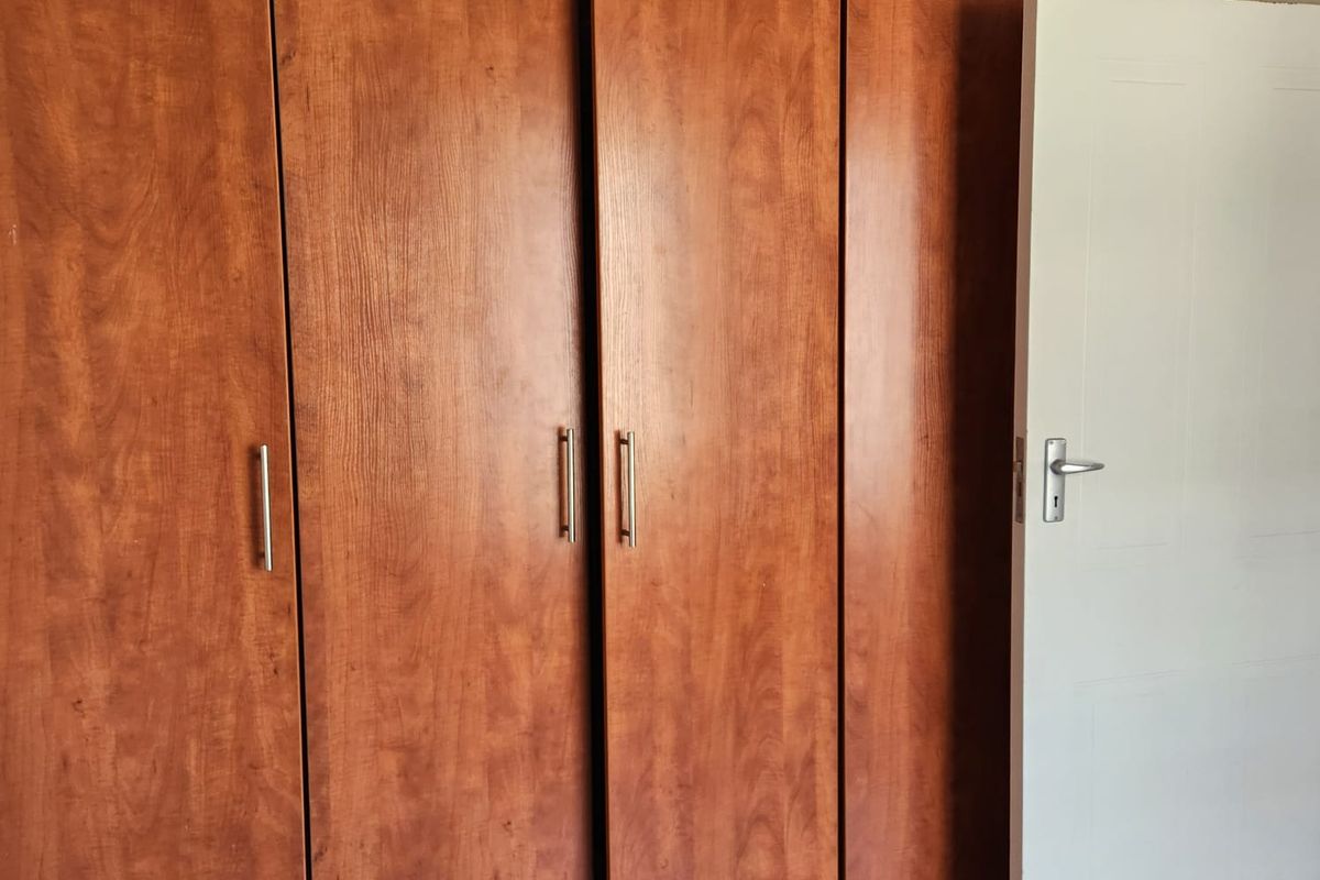 A bedroom featuring built-in wooden cabinetry with integrated storage and a standard interior door.