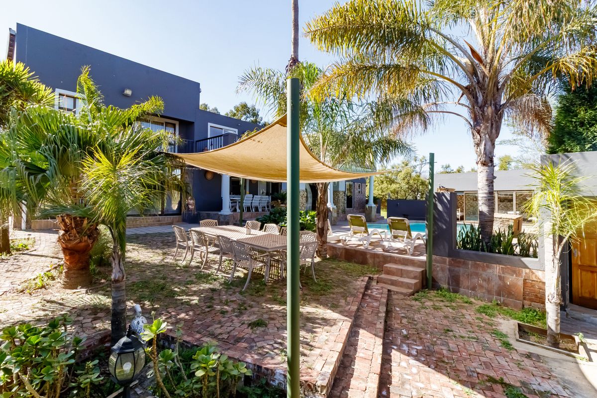 Spacious rear garden featuring a paved patio area, shade sail, and a swimming pool, ideal for outdoor entertaining.