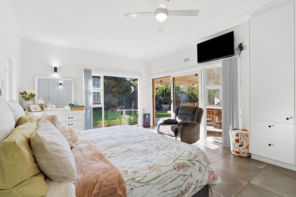 Spacious bedroom featuring large sliding glass doors that open onto a patio, built-in cabinetry, and a ceiling fan.