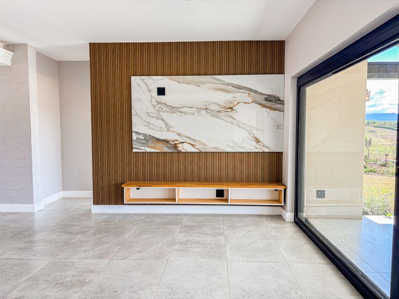Modern living area featuring a striking marble and slatted timber feature wall, built-in floating media console, and large format floor tiles with patio access.