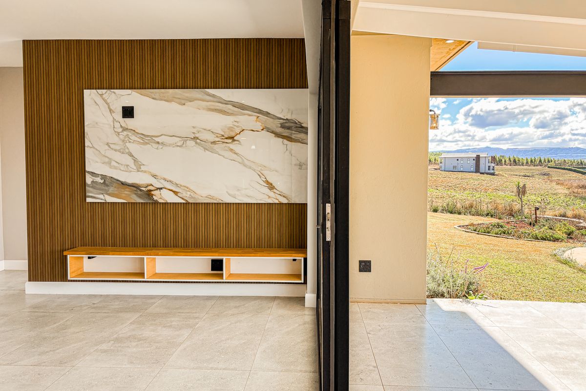 Modern living area featuring a marble accent wall, timber slat paneling, built-in floating cabinetry, and seamless access to an outdoor patio through stacking glass doors.