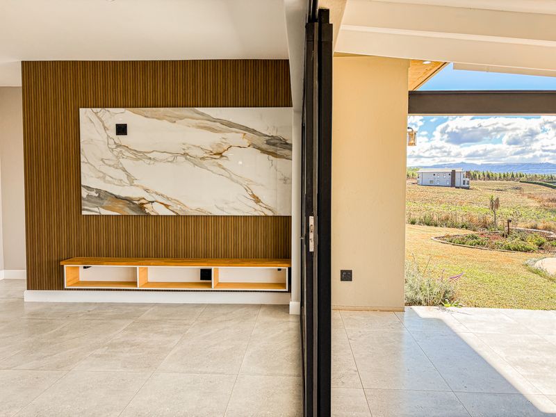 Modern living area featuring a marble accent wall, timber slat paneling, built-in floating cabinetry, and seamless access to an outdoor patio through stacking glass doors.