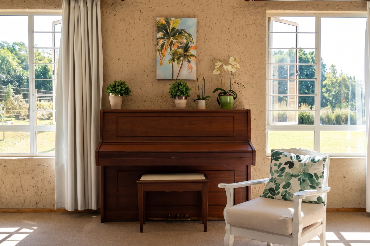 A bright living room featuring textured walls, large casement windows with security bars, and neutral carpeting, offering a view of the garden.