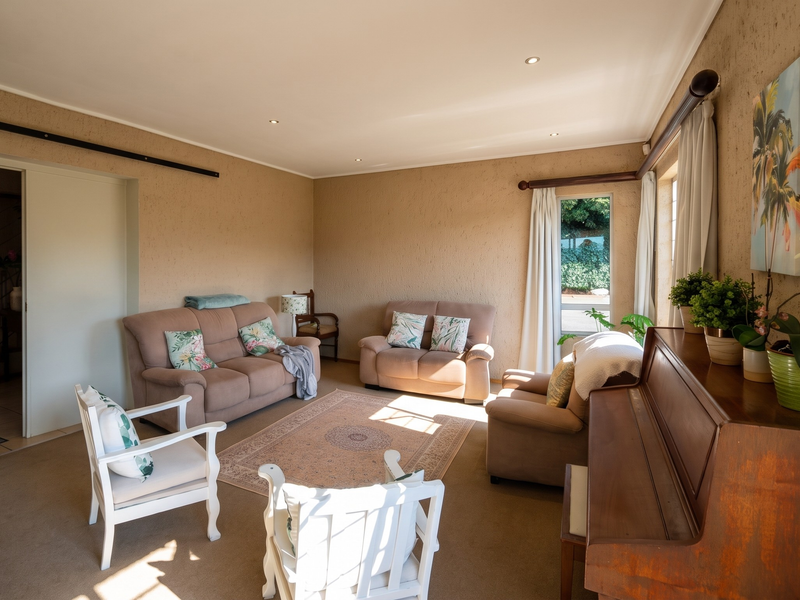 A spacious living room featuring textured walls, recessed downlighting, and carpeted flooring, offering a comfortable and well-lit area for relaxation.