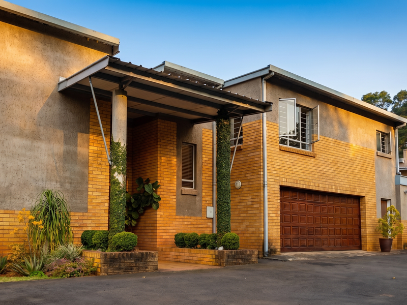 A well-maintained double-story residence featuring a face brick and plaster facade, a covered entrance with concrete columns, and an integrated double garage.