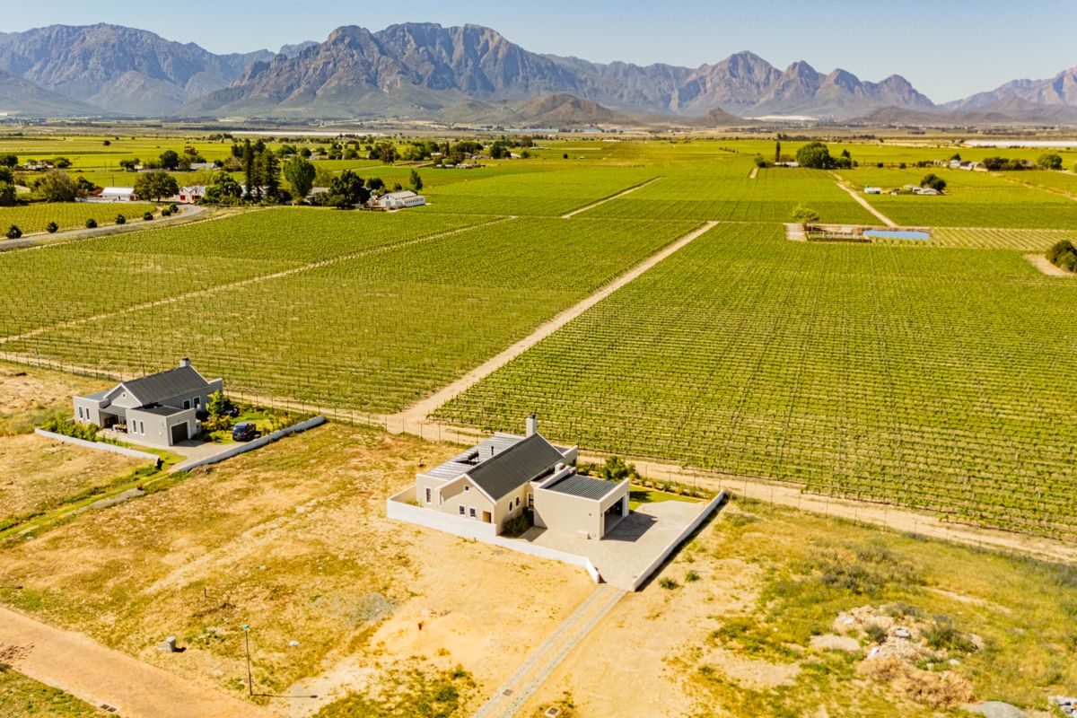 Aerial view of a residential property situated within a large vineyard landscape, featuring mountain views and established boundary fencing.
