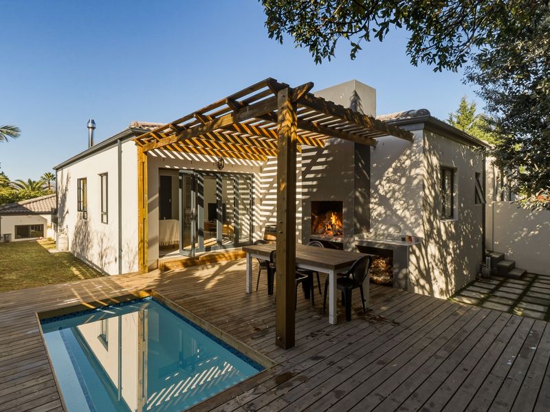 Outdoor entertainment area featuring a wooden deck, built-in braai, pergola, and a plunge pool, seamlessly connected to the interior via sliding glass doors.