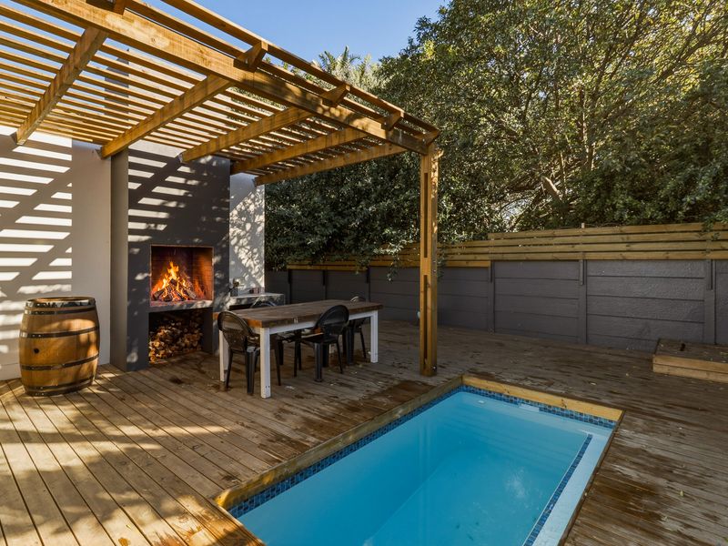 Outdoor entertainment area featuring a timber deck, built-in braai, wooden pergola, and a plunge pool, perfect for relaxed alfresco dining and leisure.