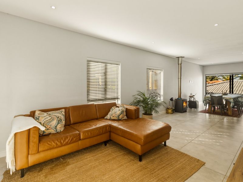 Spacious open-plan living area featuring tiled floors, recessed lighting, a modern freestanding fireplace, and large sliding doors leading to an outdoor space.