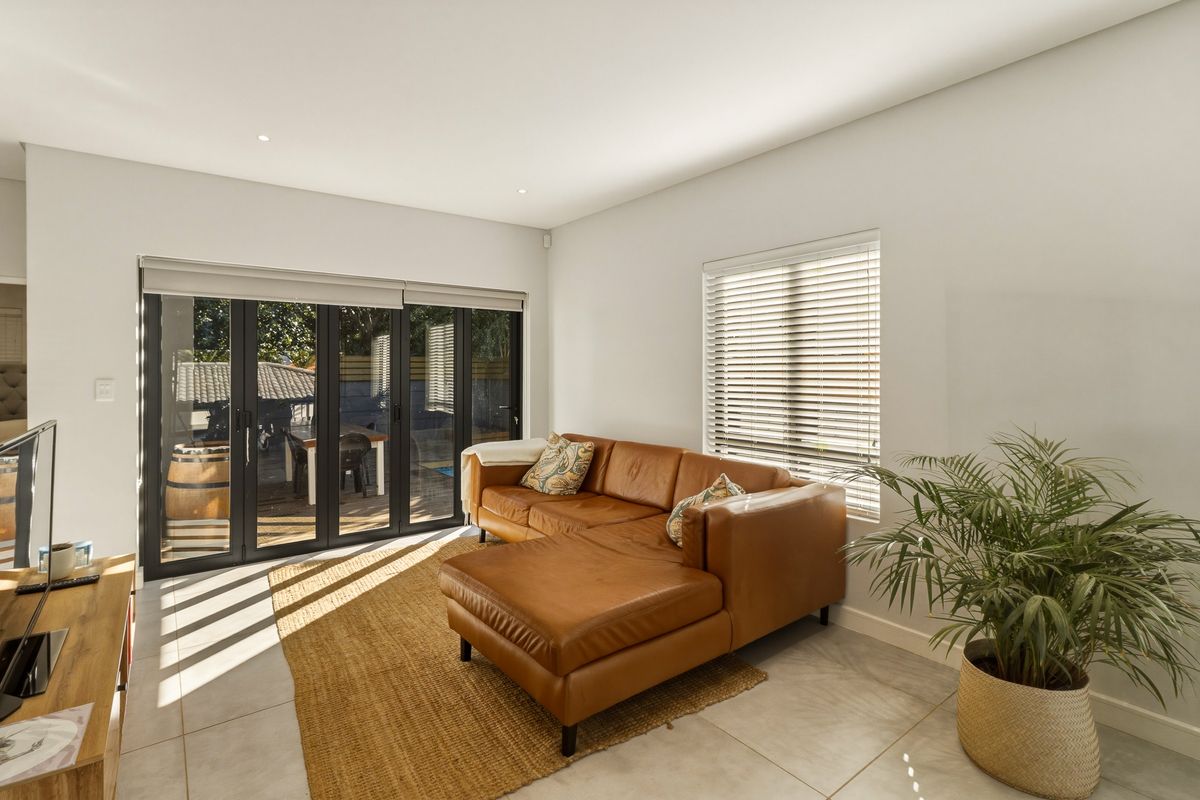 Bright living room featuring tiled flooring, recessed lighting, and black aluminium bifold doors providing seamless access to the outdoor patio area.