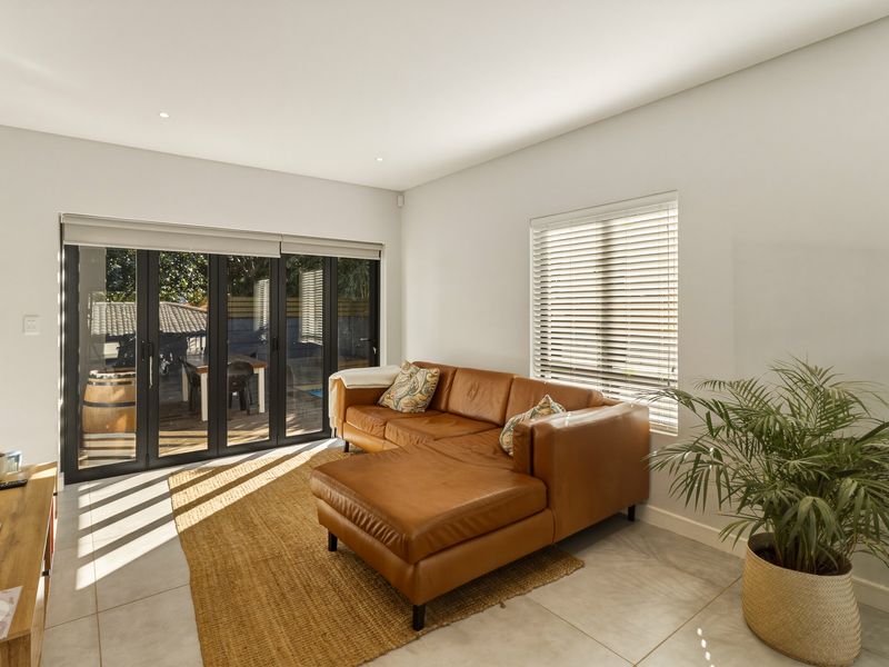 Bright living room featuring tiled flooring, recessed lighting, and black aluminium bifold doors providing seamless access to the outdoor patio area.