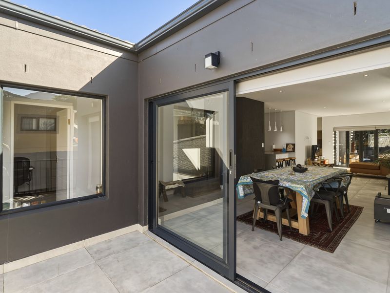 A modern covered patio area featuring large sliding glass doors that provide seamless indoor-outdoor flow into the open-plan living and dining space.