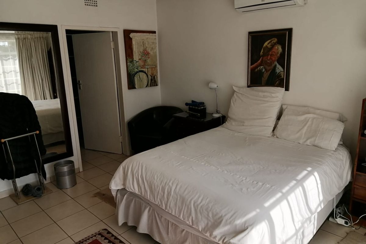 A functional bedroom featuring tiled flooring and a wall-mounted air conditioning unit.