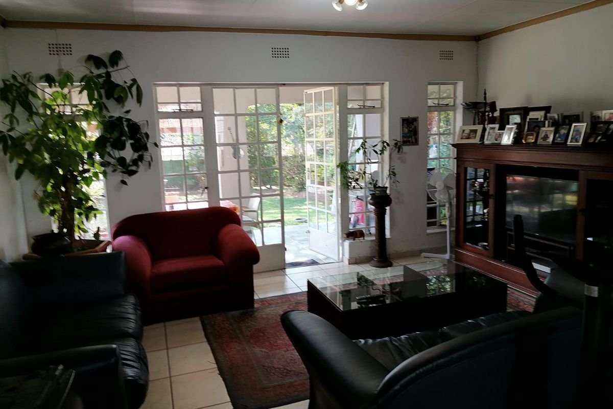 A living room featuring tiled flooring and french doors providing direct access to the garden area.