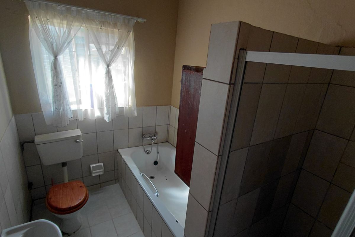 A functional bathroom featuring a bathtub, separate shower enclosure, and toilet with neutral wall tiling.