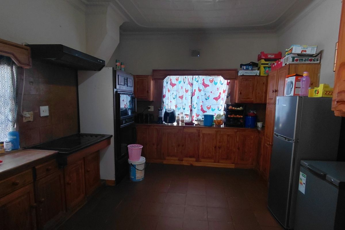 A traditional kitchen featuring extensive wooden cabinetry, built-in oven, extractor fan, and tiled flooring, offering a functional layout with potential for modern updates.