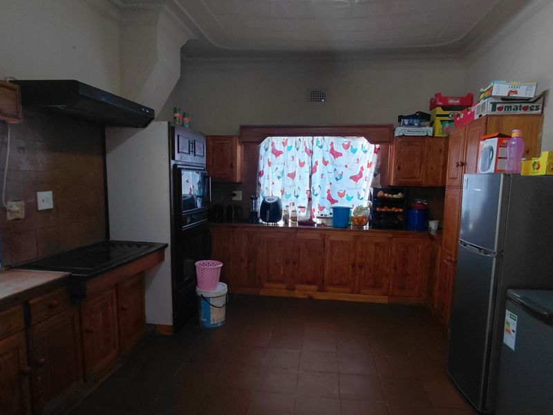 A traditional kitchen featuring extensive wooden cabinetry, built-in oven, extractor fan, and tiled flooring, offering a functional layout with potential for modern updates.
