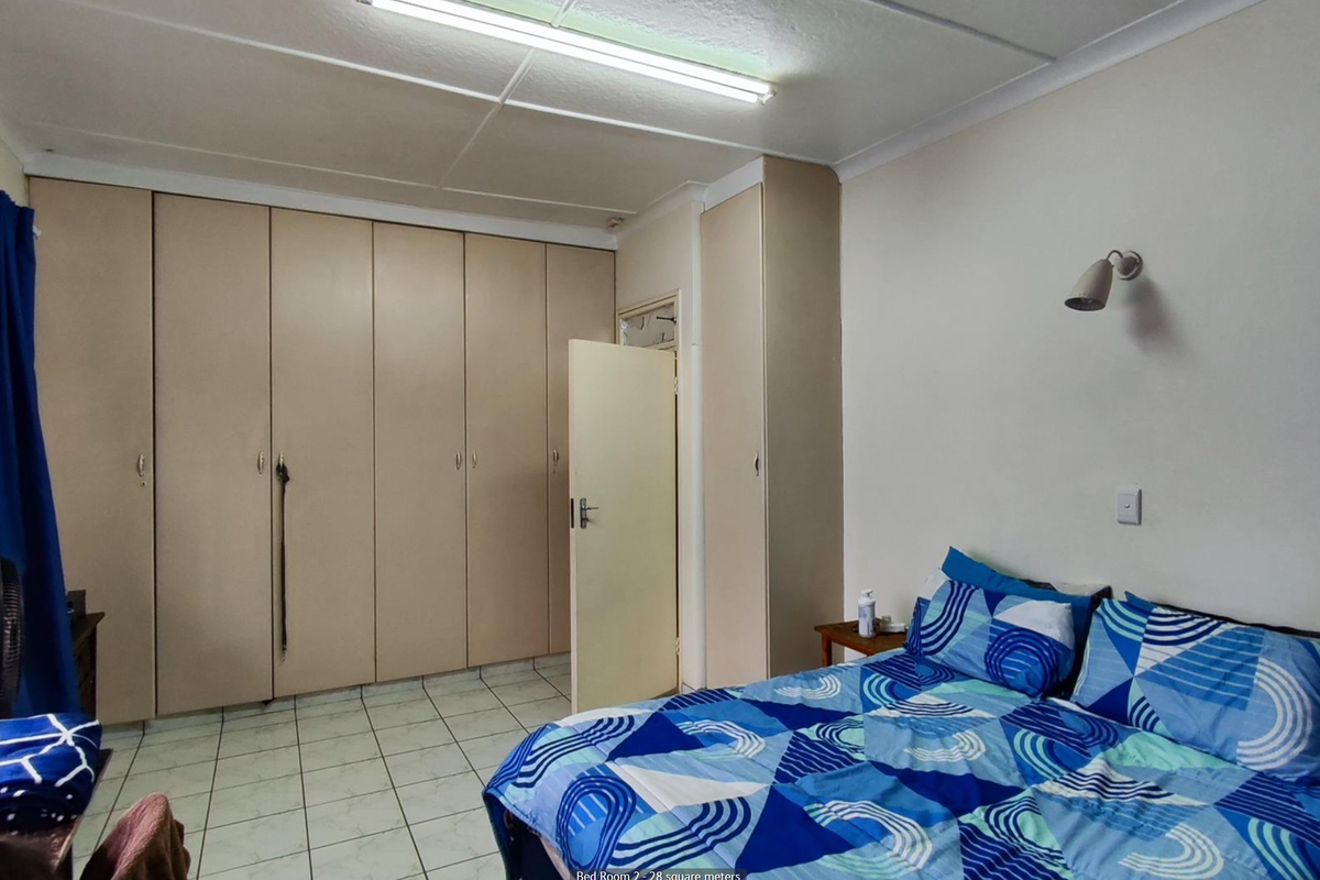 A bedroom featuring extensive built-in cupboards, tiled flooring, and a wall-mounted light fixture.