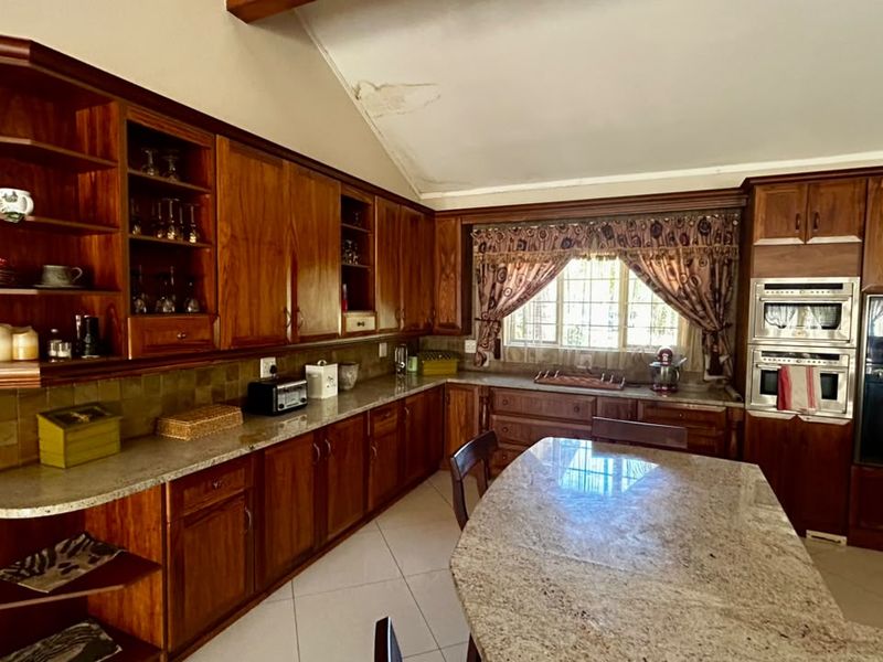 Spacious kitchen featuring extensive wooden cabinetry, granite countertops, and a built-in double oven, with a vaulted ceiling showing signs of water damage.