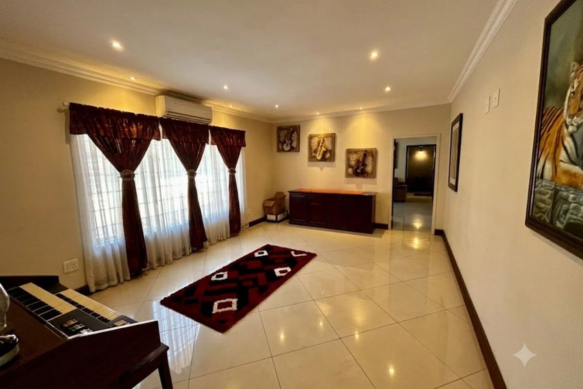 Spacious living area featuring polished tiled flooring, recessed downlighting, and a wall-mounted air conditioning unit, providing a comfortable and well-maintained interior space.