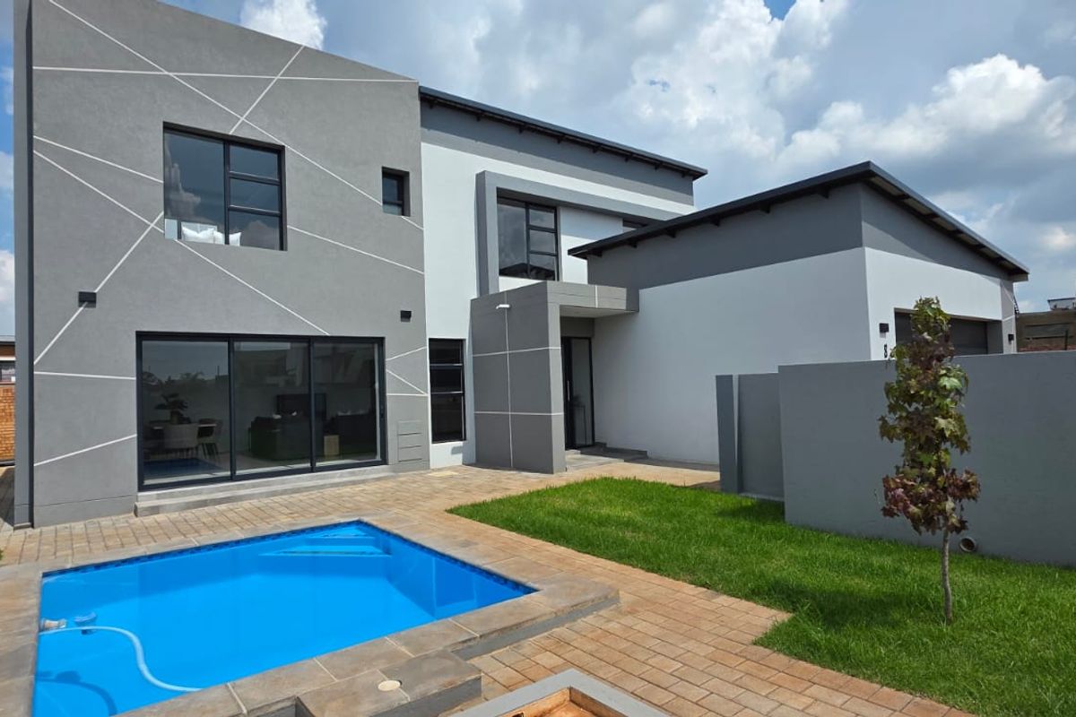 Modern double-storey home featuring a private swimming pool, paved patio area, and contemporary grey and white exterior facade with large sliding glass doors.