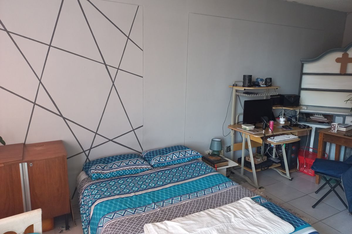A bedroom featuring tiled flooring and a textured ceiling, with a decorative geometric wall accent.
