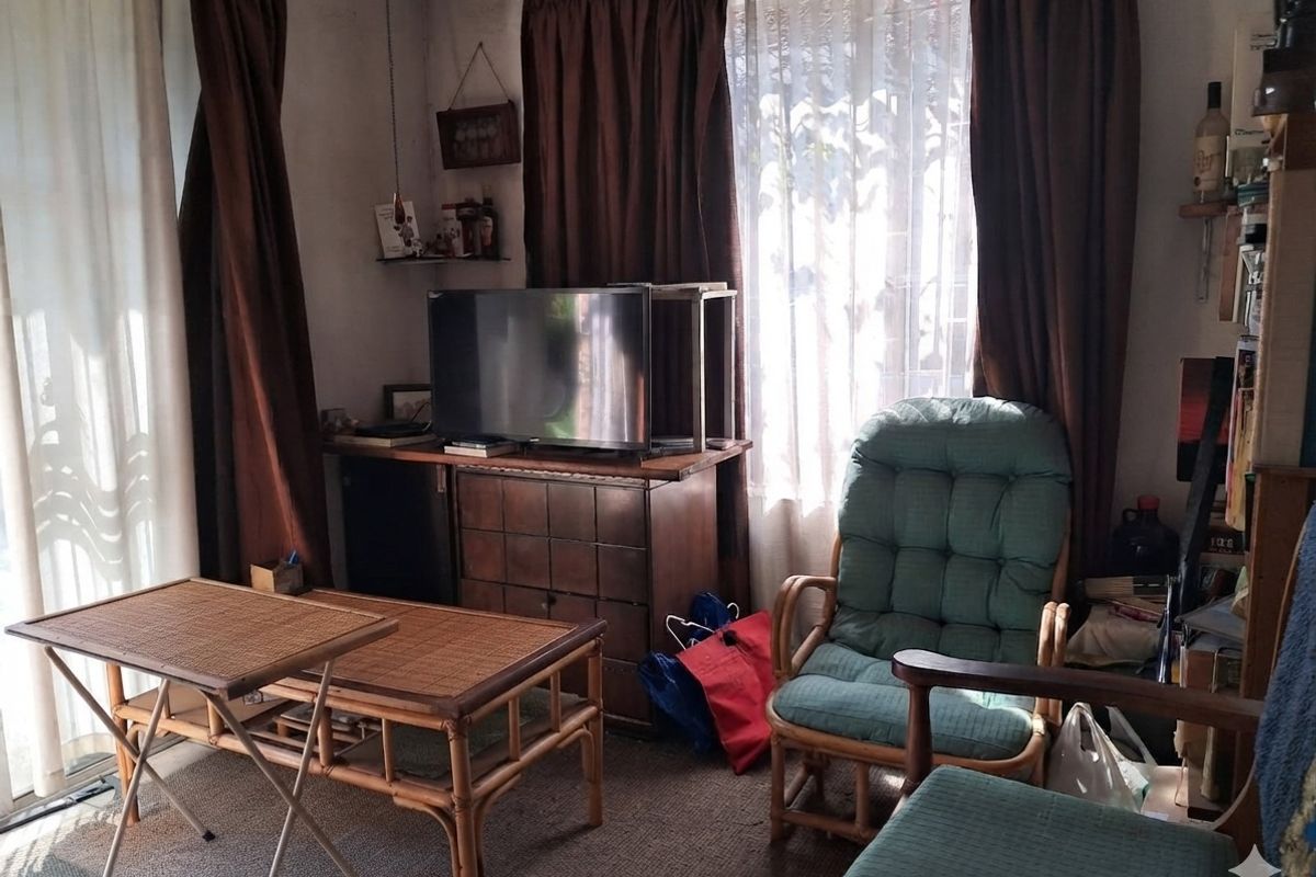 A living room area featuring carpeted flooring and a sliding glass door providing natural light, currently requiring cosmetic updates to modernize the space.