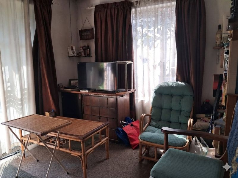 A living room area featuring carpeted flooring and a sliding glass door providing natural light, currently requiring cosmetic updates to modernize the space.