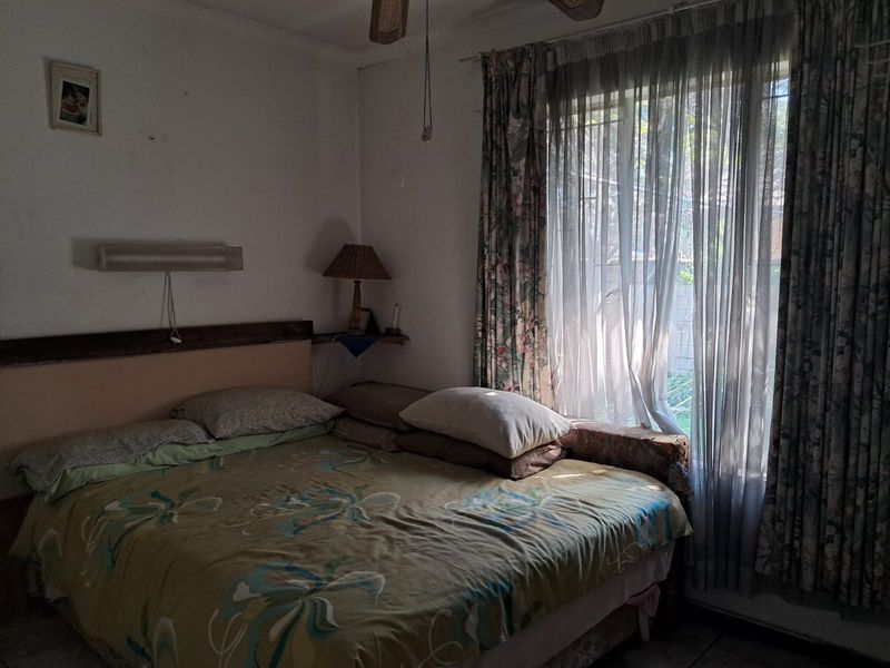A bedroom featuring a ceiling fan and window security bars, requiring cosmetic updates to improve the overall condition and aesthetic appeal.