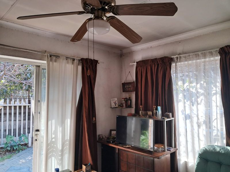 A living room area featuring a ceiling fan and sliding glass door access to the exterior, requiring cosmetic updates to walls and ceiling finishes.