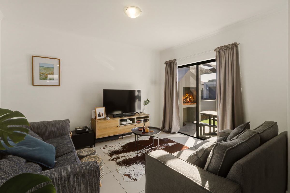 A bright and well-maintained living room featuring tiled flooring and a sliding glass door that opens to an outdoor patio area.