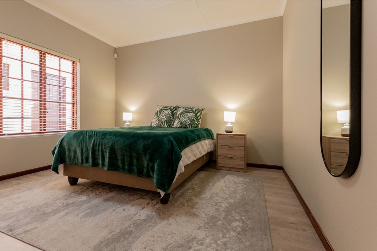 A well-maintained bedroom featuring neutral wall tones, laminate flooring, and a window fitted with blinds, providing a clean and comfortable living space.