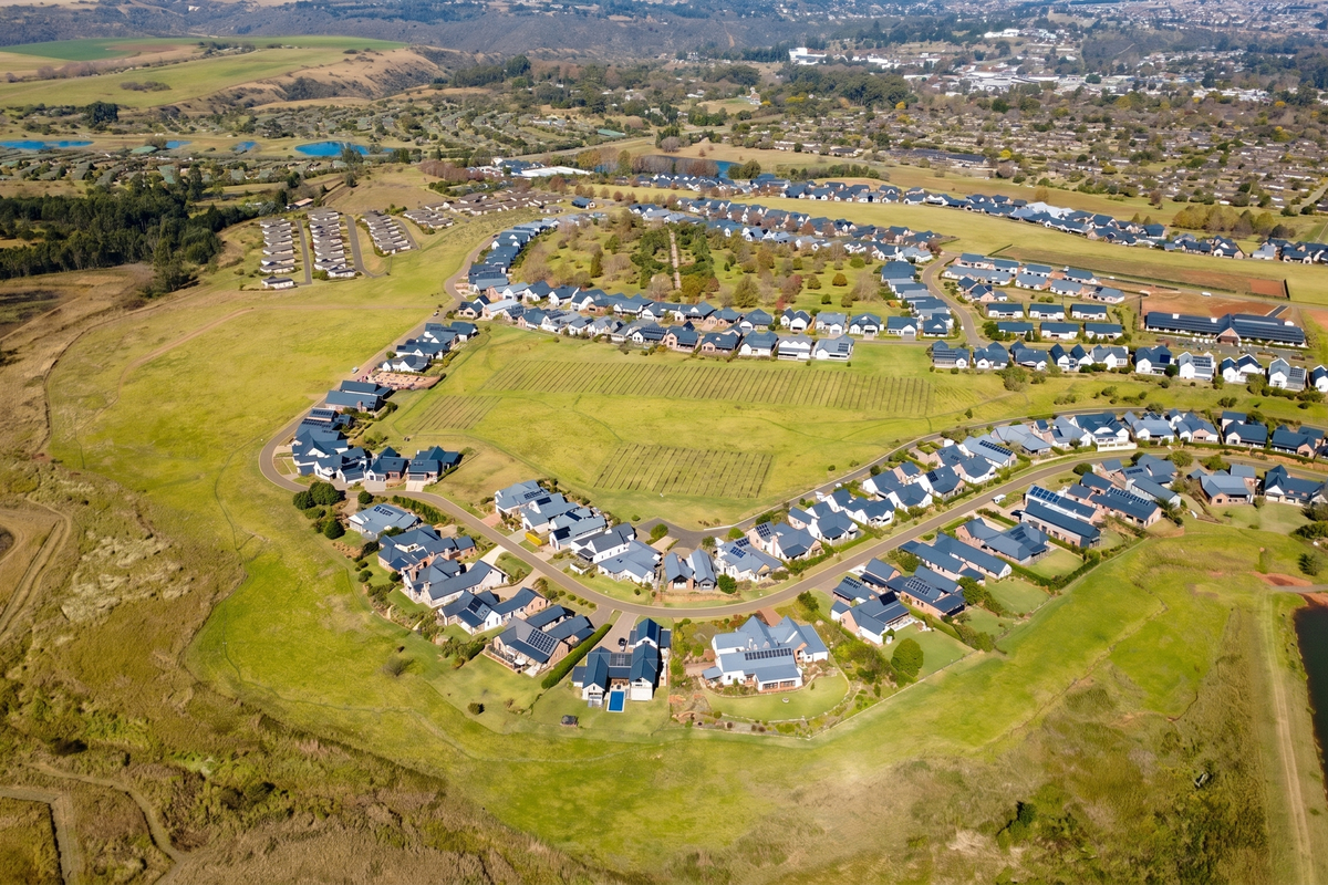 An aerial view of a residential estate featuring established homes, landscaped green spaces, and surrounding natural landscape.