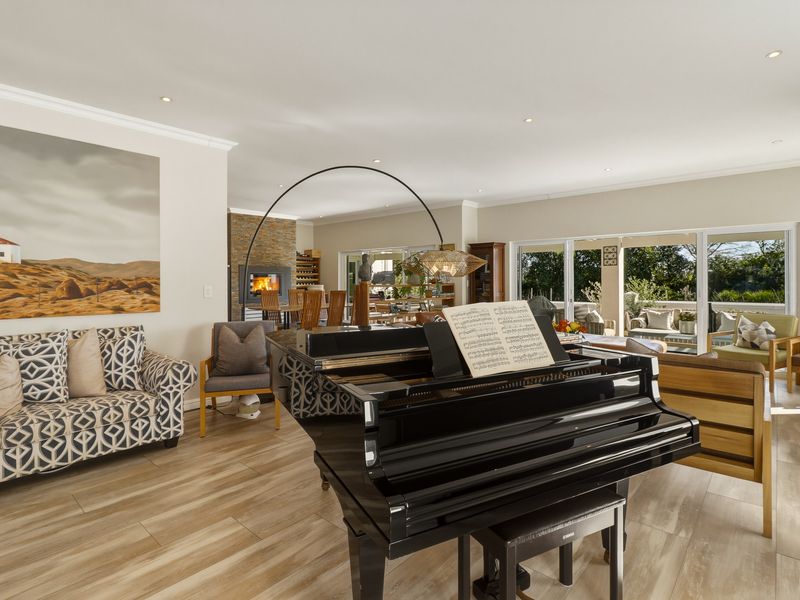 Spacious open-plan living area featuring wood-look tile flooring, a built-in fireplace with stone cladding, and large sliding glass doors leading to the patio.