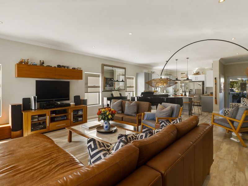 Spacious open-plan living area featuring a modern kitchen with a breakfast island, recessed lighting, and light wood-look flooring throughout.