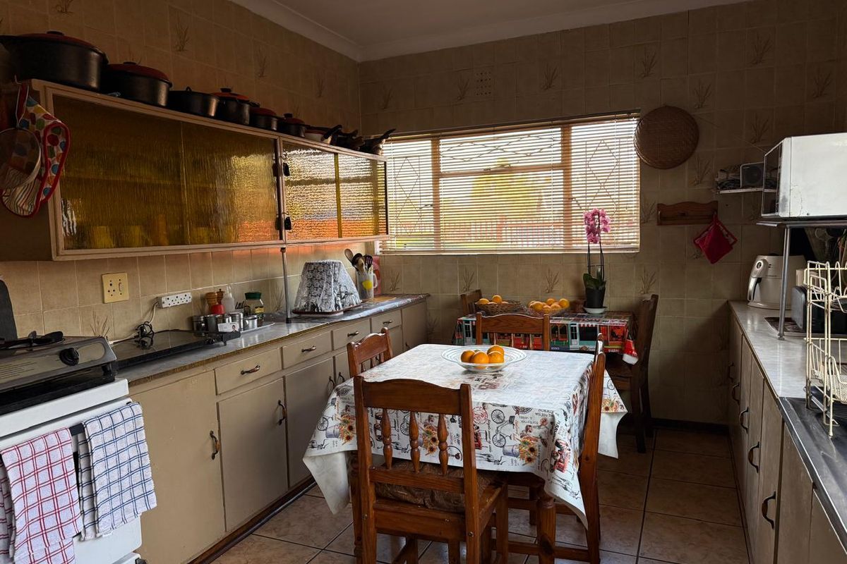 A dated kitchen featuring original cabinetry, tiled walls, and tiled flooring, offering a functional layout with potential for modern renovation.
